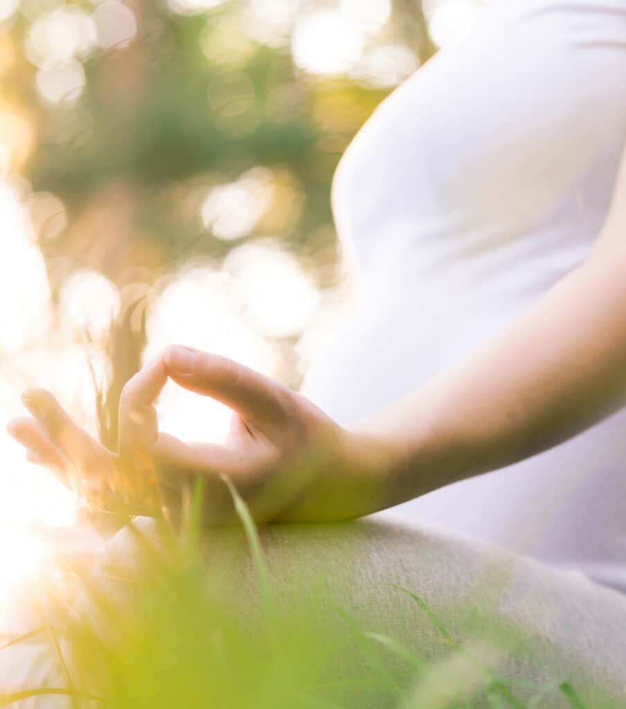 pregnant woman meditating in grass