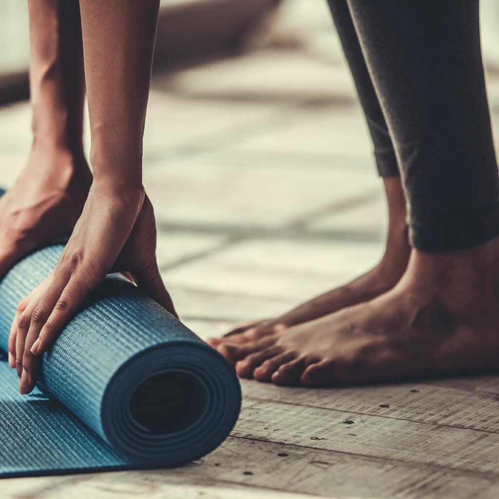 Closeup of someone rolling up their  yoga mat on the ground