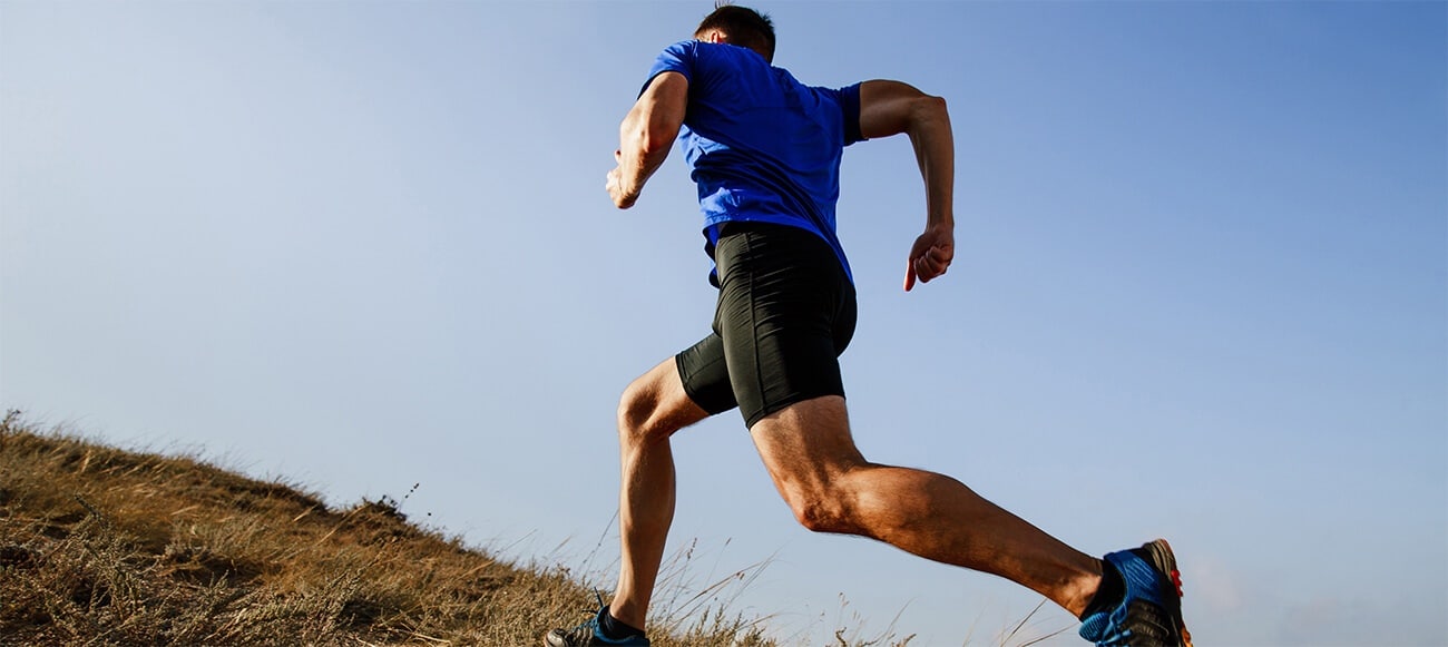 A man in a blue shirt runs up a hill