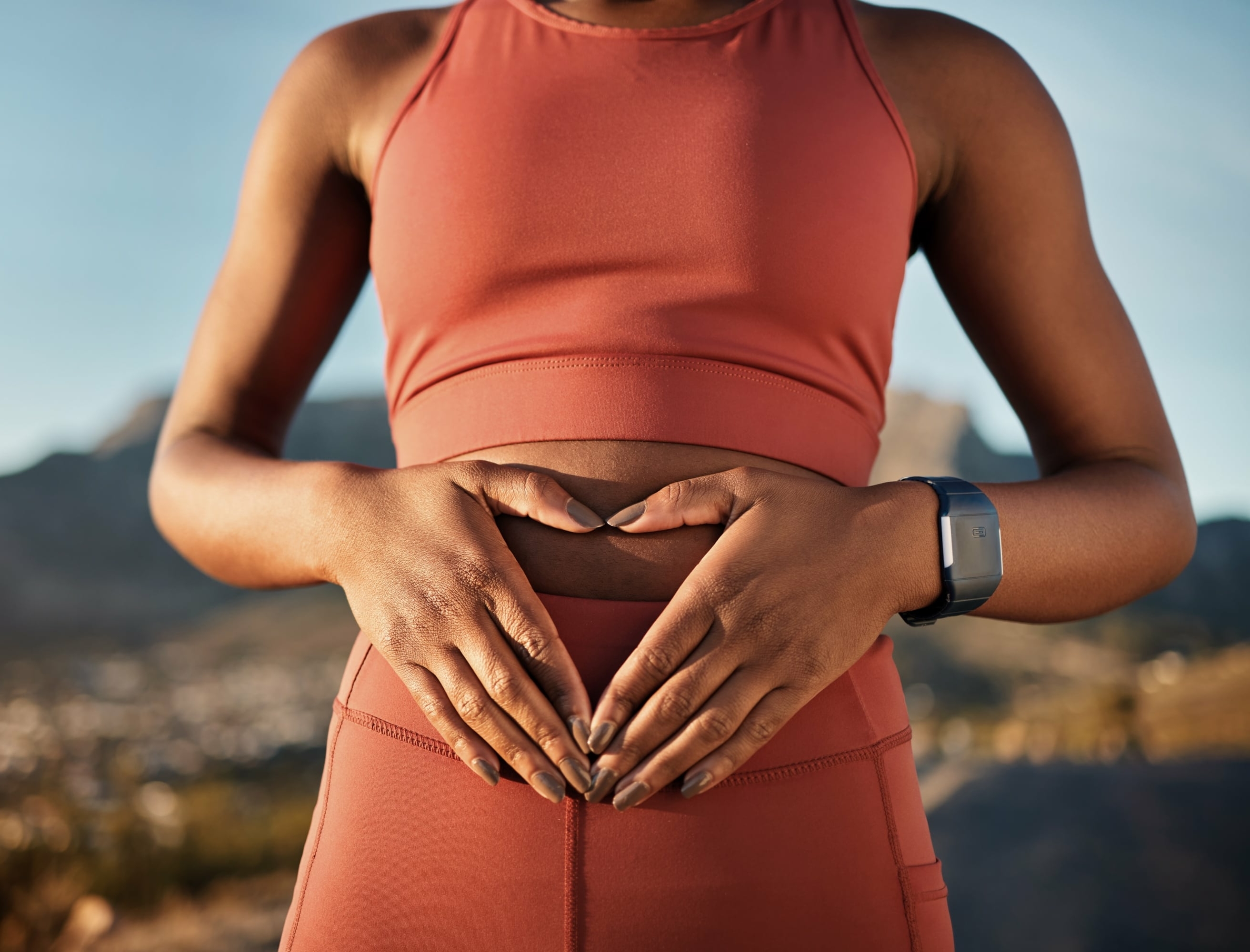 girl makes a heart out of her hands over her stomach