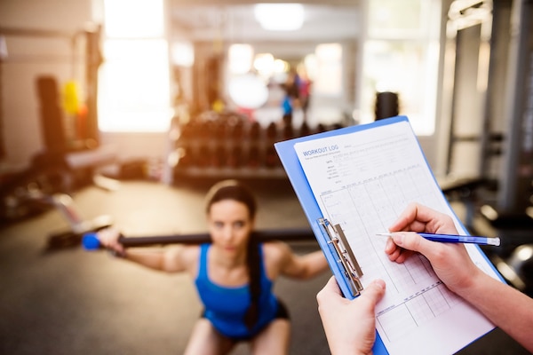 Trainer looking at his workout program while his client works out