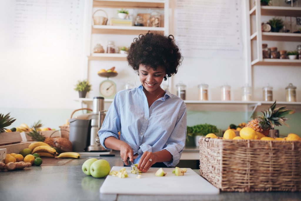 Woman in kitchen chopping fruit on a cutting board