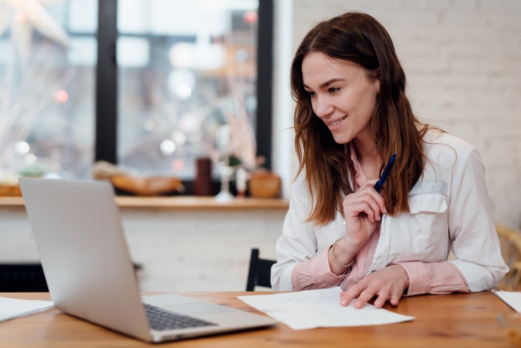 woman sitting at a desk with a laptop and a piece of paper