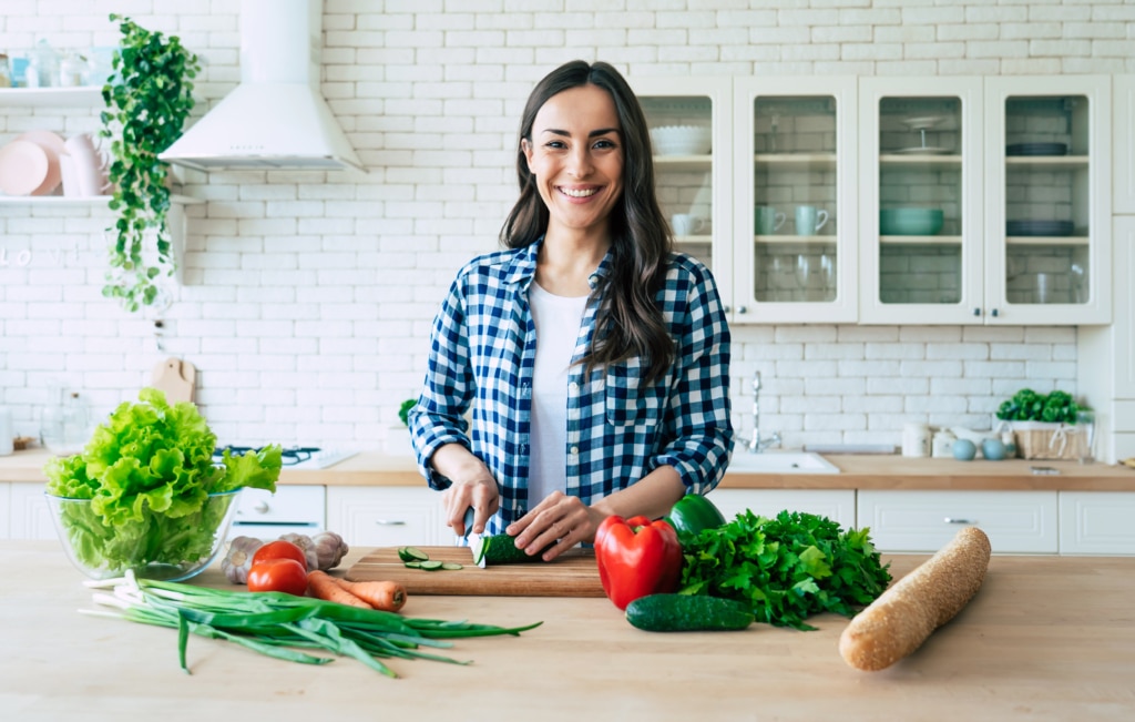 young woman preparing vegetable salad in the kitchen