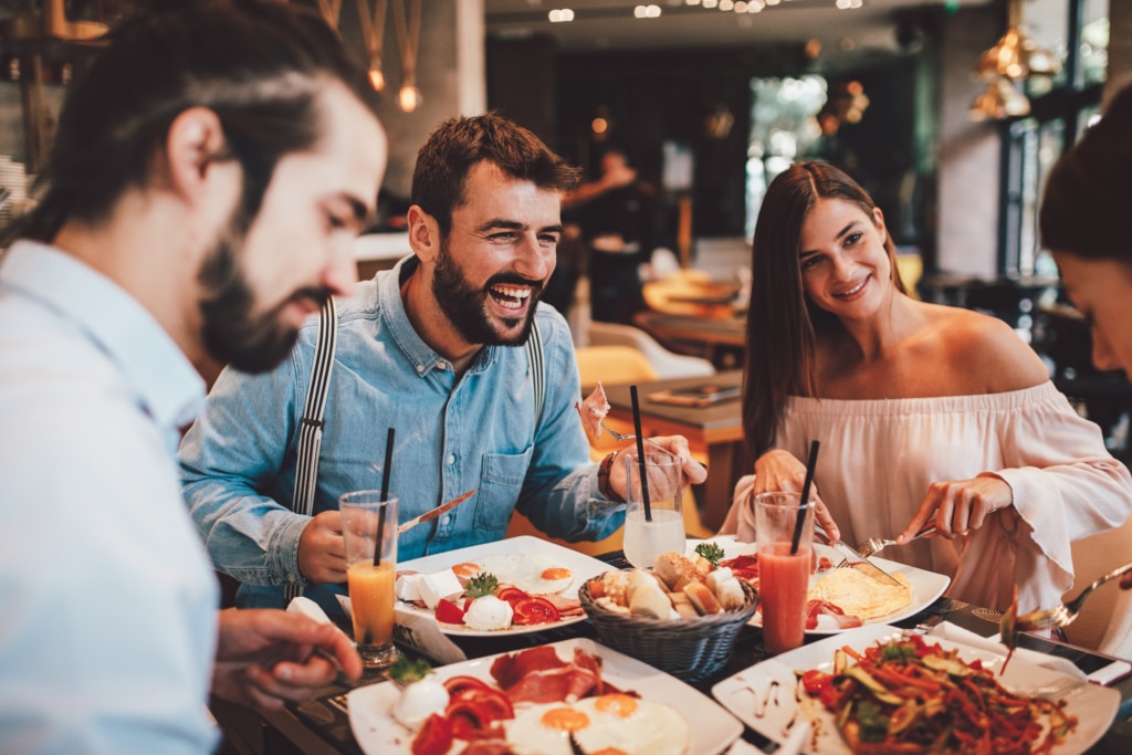 group of happy friends at a restaurant eating and drinking