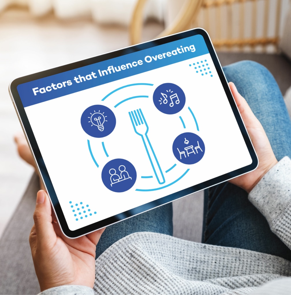 person holding a tablet with "factors that influence overeating" cover on display