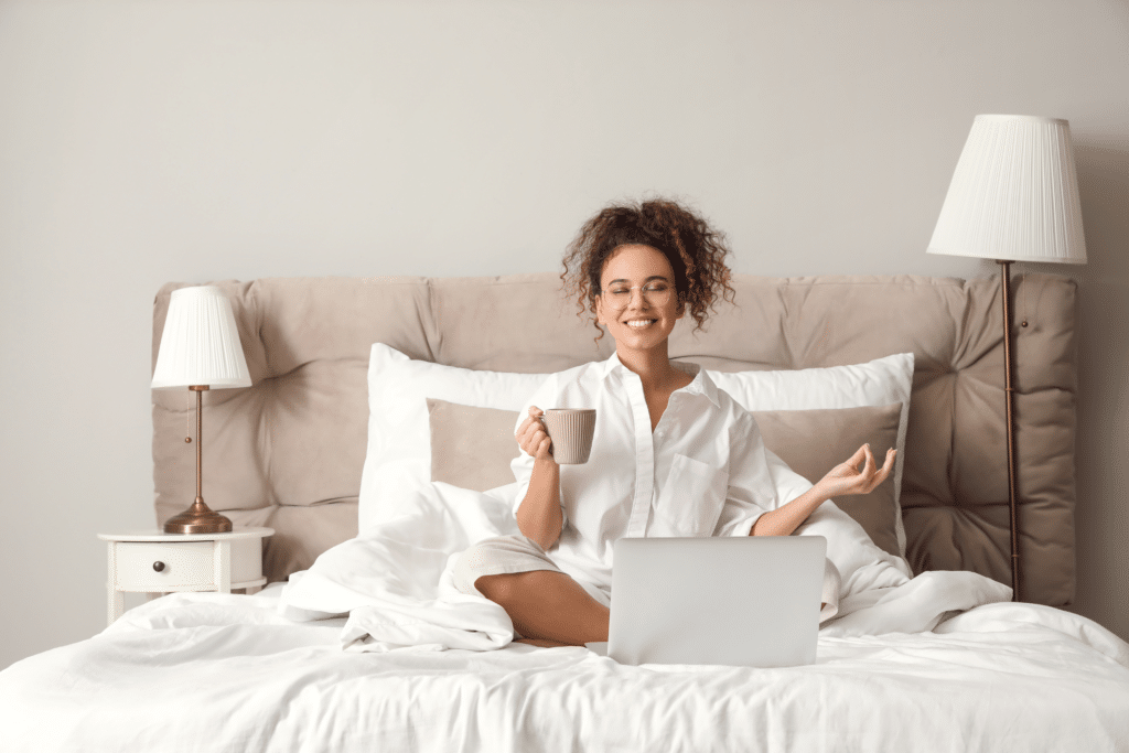 woman meditating in bed with laptop