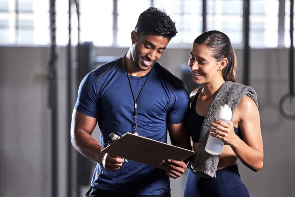 AFPA Certified Personal Trainer with Clipboard and Client in the Gym