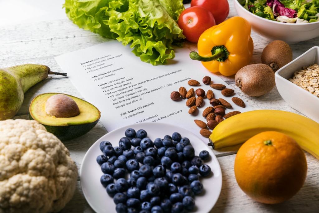 display of healthy food - blueberries, avocado, orange, banana, nuts, bell pepper, cauliflower, leafy greens