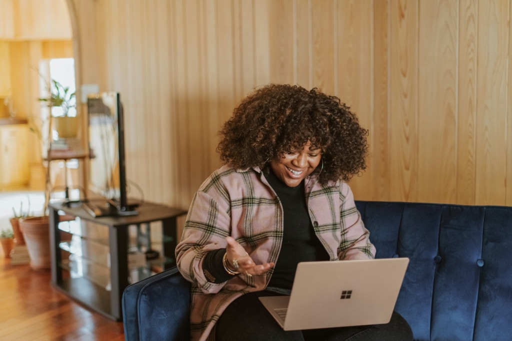 woman sitting on blue couch with laptop on her lap