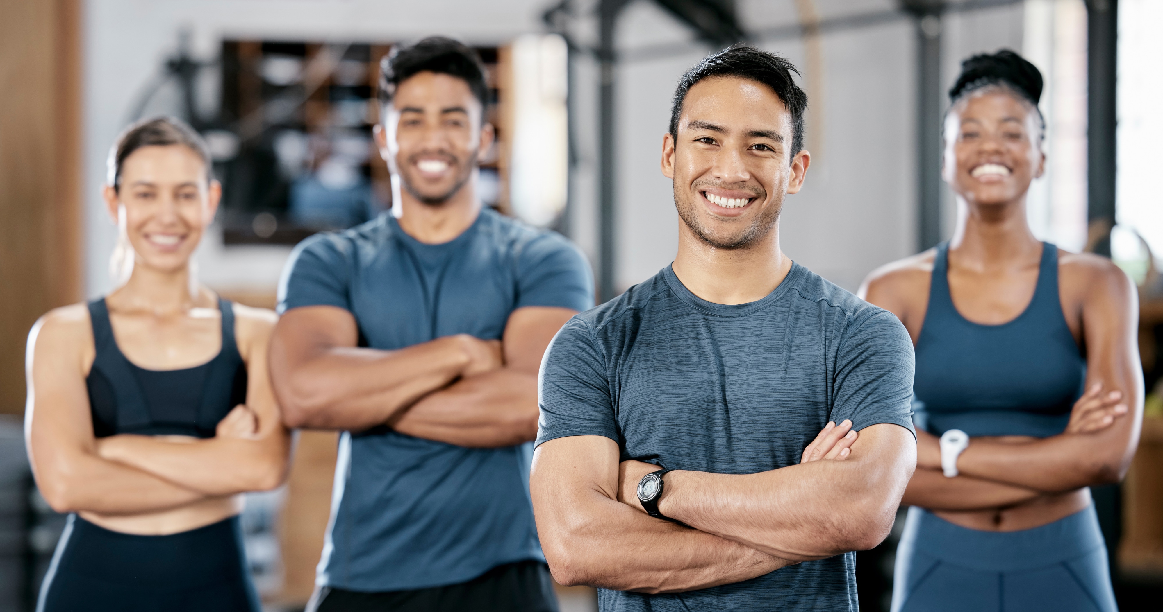 four personal trainers standing in gym with arms crossed