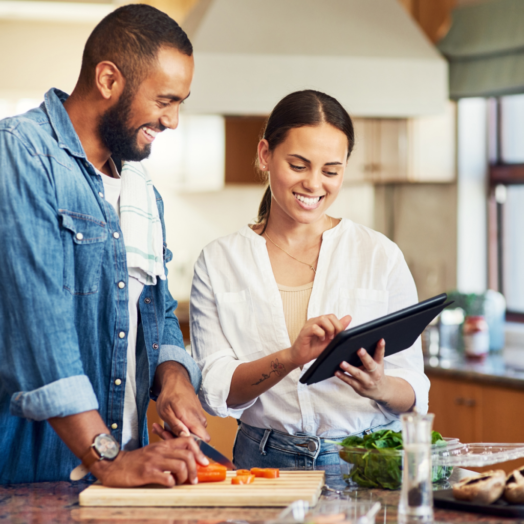 AFPA Certified Holistic Nutrition Coach Holding Tablet in Kitchen with Client While Preparing Food